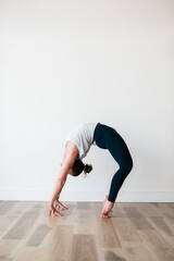 flexible woman holding wheel yoga pose in gym 