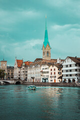 Old town in Zurich city, Switzerland. Panorama of river, bridge, church with a spire and embankment with historic buildings. Pleasure boat. Swiss vacation.