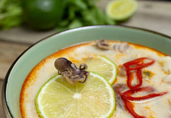 Tom yum soup close-up: baby octopus on a slice of lime, chili peppers in tom yum soup