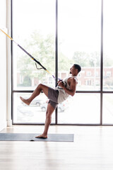 Fototapeta na wymiar Man holding pose using TRX bands in yoga studio holding pose strength training on one leg