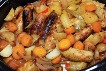 Pork Sausages And Vegetables Cooking In A Casserole Dish.