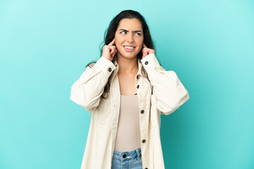 Young caucasian woman isolated on blue background frustrated and covering ears