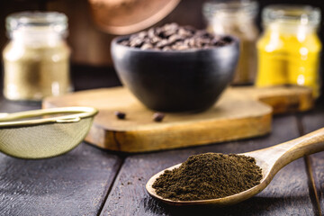 golden spoon with Brazilian coffee powder and roasted seeds in the background