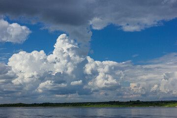 Powerful clouds over the bed of a large river in summer