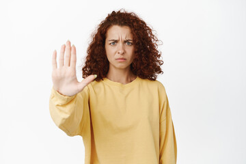Stop. Displeased young woman stretch out one hand, palm restriction, taboo gesture, frowning from...