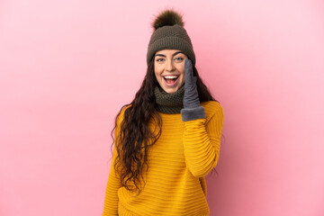 Young caucasian girl with winter hat isolated on purple background shouting with mouth wide open