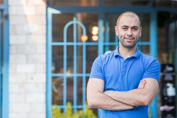 Confident and serious looking man posing in front of his shop or business, includes copy and text space.