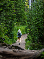 Solo traveling young female hiking in the woods, blonde female exploring the forest. Portrait crop