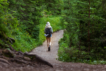 Obraz premium Solo traveling young female hiking in the woods, blonde female exploring the forest