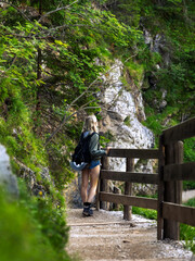 Young carefree female tourist holding wooden barrier enjoying the view on the stairs