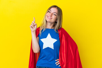 Super Hero Romanian woman isolated on yellow background showing and lifting a finger in sign of the best