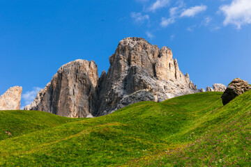 Fototapeta na wymiar 2 big rocky mountain peaks rising up in the lush green hills of grass in the Dolomite mountains