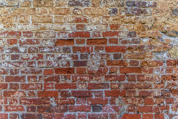 abstract background of an old shabby red brick wall painted yellow close up