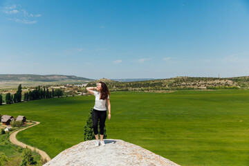 a beautiful woman looks at the view on top of a cliff on a cliff on a journey