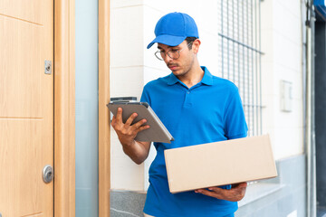 Young delivery man at outdoors holding boxes and a tablet