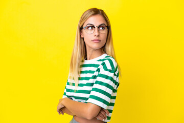 Blonde Uruguayan girl isolated on yellow background keeping the arms crossed