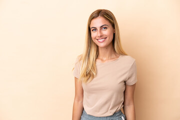 Blonde Uruguayan girl isolated on beige background laughing