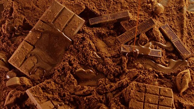 Chocolate sauce pouring, dripping Into chocolate bar and cacao powder in Slow motion . Chocolate composition background .