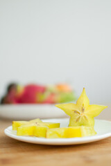 Exotic starfruit or averrhoa carambola on white plate on wooden cut board. Healthy food, fresh organic star apple fruit.