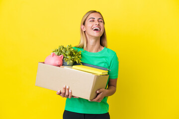 Young Uruguayan girl making a move while picking up a box full of things isolated on yellow...