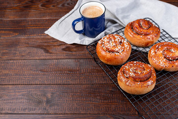 Freshly baked traditional Swedish cinnamon buns Kanelbulle with cup of coffee or cappuccino, on...