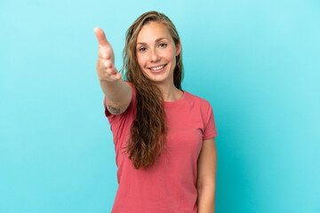 Young caucasian woman isolated on blue background shaking hands for closing a good deal