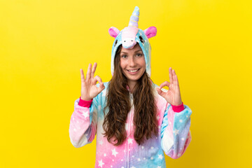 Girl with unicorn pajamas over isolated background showing an ok sign with fingers