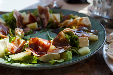 Sweet salad with dry-cured ham, pear and cheese, soft focus background