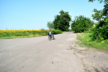 village landscape, girl rides a bike