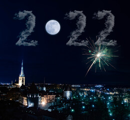 New Year's Eve card with moon and clouds of 2022 and fireworks salute above a night city