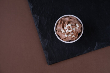 Delicious chocolate cupcake with cream and white chocolate sprinkling on a dark background. Sweets for a party.