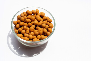 Crispy peanut snack balls in glass bowl on white background.