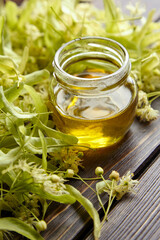 Honey in glass jar and linden flowers on wooden table. Sweet fragrant honey