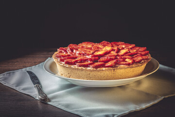 Homemade strawberry pie with syrup on a ceramic platter.