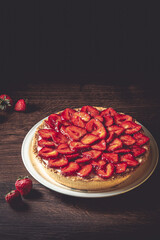 Homemade strawberry pie with syrup on a ceramic platter.