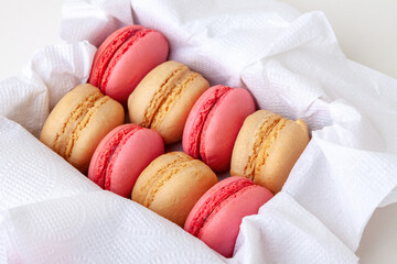 Macaroni cakes with vanilla and strawberry filling in a box close-up.