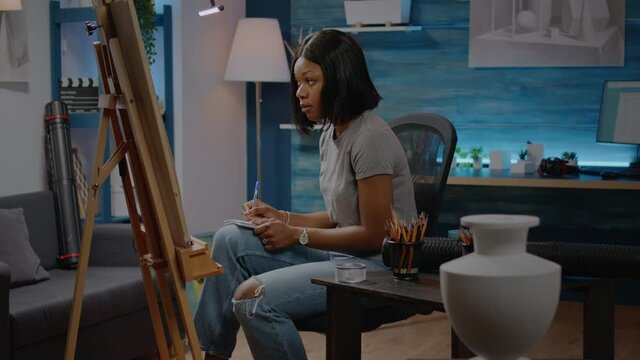 African american woman drawing vase on canvas in art studio at home. Black young artist creating modern masterpiece for fine art project and workshop concept using creativity tools