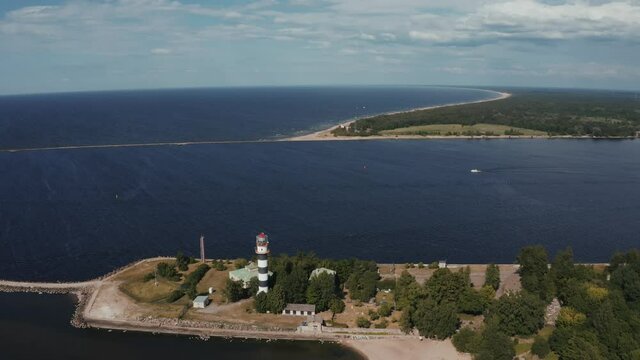 Aerial view of the lighthouse and mole at river Daugava in Latvia. Flying over river that meets the sea.