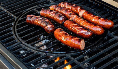 Holiday grilling of sausages in the garden. Baking the best Polish traditional sausage on a grill. Selective focus and horizontal frame.