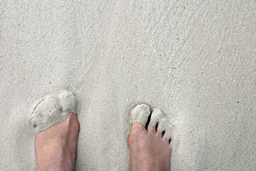 Füße im Sand. Eine Frau genießt es mit den Füßen im warmen weichen Sandstrand zu stehen