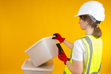 Worker women during work. He is holding a smartphone and boxes in his hands. Worker women on a yellow background. Girl in a yellow vest. Concept - uniform for worker women. Warehouse company employee