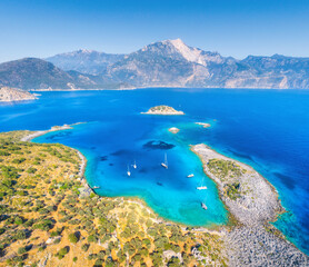 Fototapeta na wymiar Aerial view of beautiful sea bay, yachts and boats at sunset in summer. Akvaryum koyu in Turkey. Top view of luxury yachts, sailboats, clear blue water, rock, sky, mountain and green trees. Travel