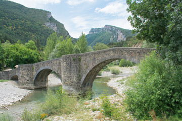 Photograph of a typical landscape of Navarra, Spain with a Roman-style bridge in a natural and mountain environment