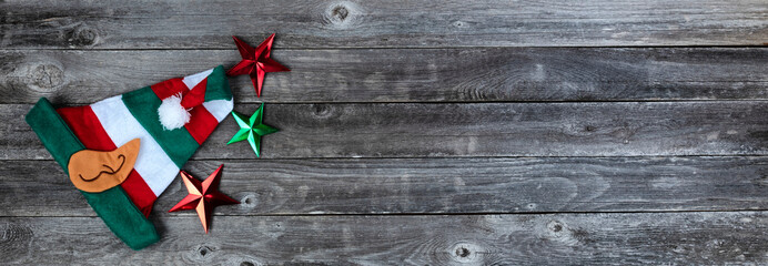 Fototapeta na wymiar Elf cap and star shapes on faded wood for merry Christmas or happy New Year holiday celebration
