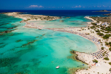 Fototapeta na wymiar Aerial view of a beautiful but busy sandy beach and shallow lagoons surrounded by clear, blue ocean (Elafonissi, Crete)