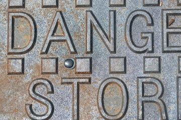 partial inscription on a manhole cover: danger storm