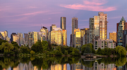 Obraz na płótnie Canvas View of Lost Lagoon in famous Stanley Park in a modern city with buildings skyline in background. Colorful Sunset Sky. Downtown Vancouver, BC, Canada.
