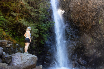 Adult Woman hiker at Norvan Falls and river stream in the natural canyon during the summer time. Canadian Nature Background. Lynn Valley, North Vancouver, BC, Canada.