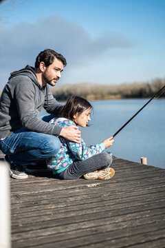 padre e hija disfrutando pesca en muelle a orillas del rio Paran&aacute; en tarde soleada de invierno