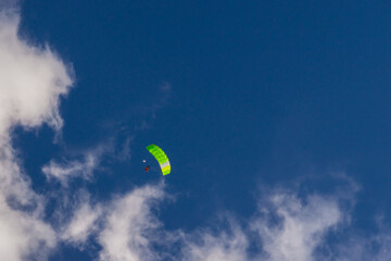 green parachute against the background of blue sky and clouds